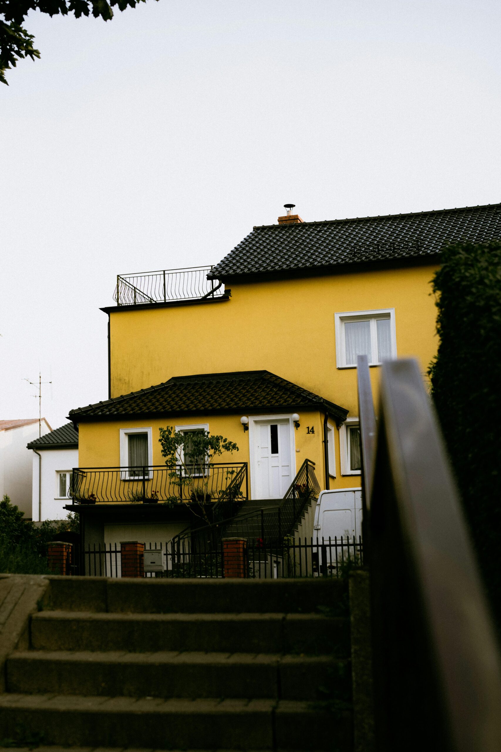 Close-up of a yellow house facade with a balcony and stairs, perfect for architectural stock photos.