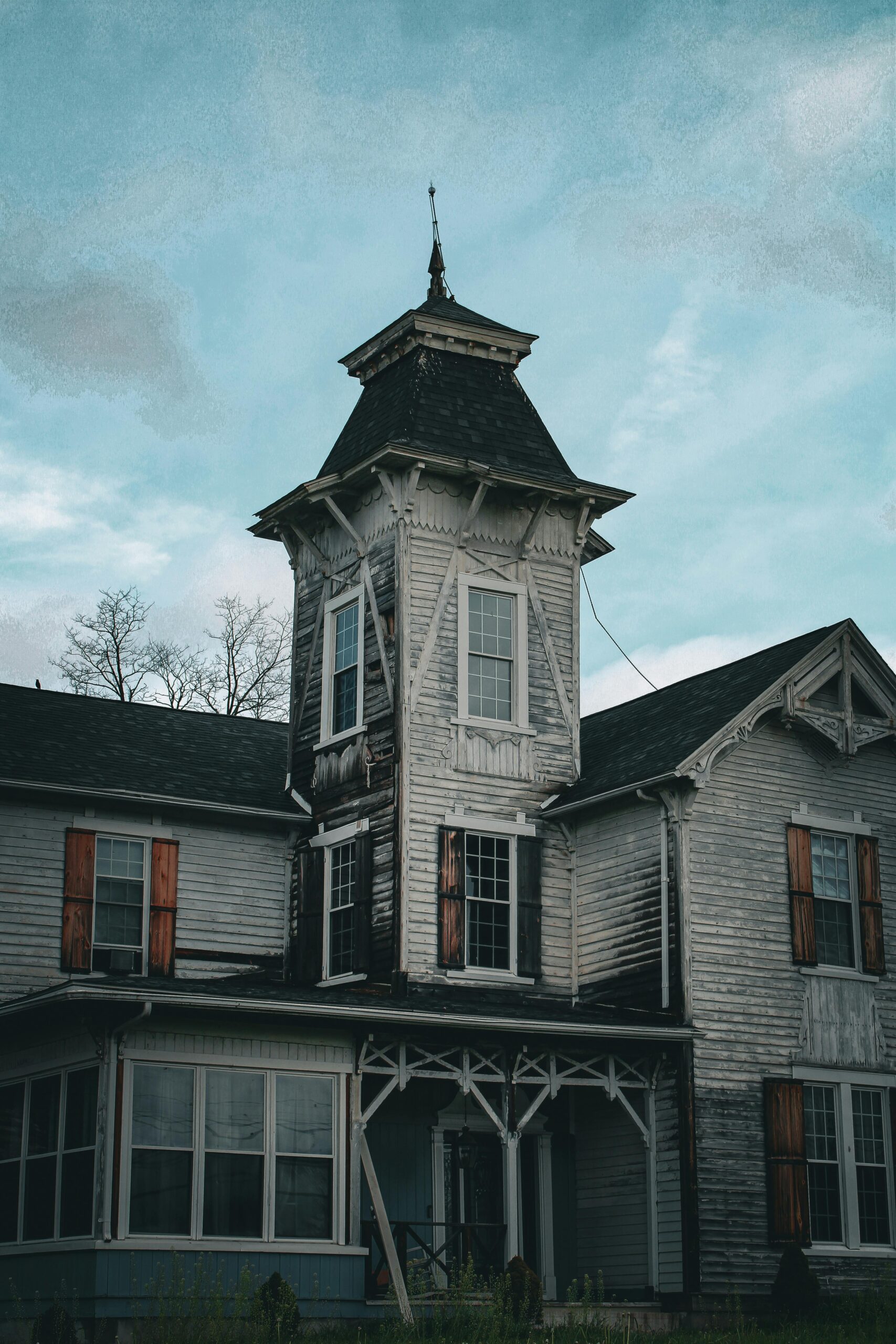 Eerie Victorian house with weathered facade and tall tower, capturing a sense of mystery.