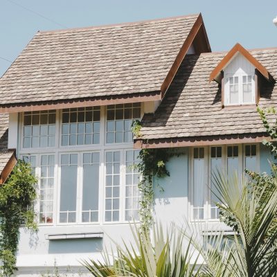 Elegant suburban house with large windows and a shingled slate roof in sunlight.